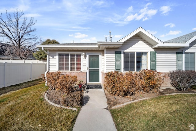 view of front of house featuring fence, a front lawn, and brick siding