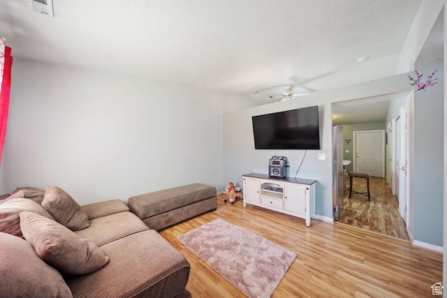 living area featuring ceiling fan, lofted ceiling, visible vents, baseboards, and light wood finished floors