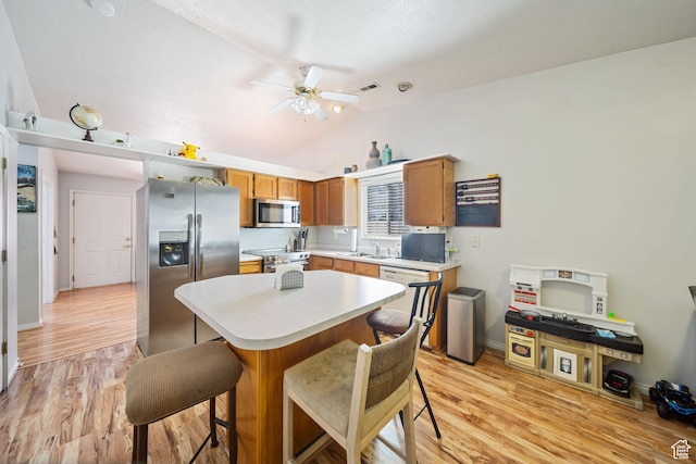 kitchen featuring stainless steel appliances, a breakfast bar, light countertops, and light wood-style floors