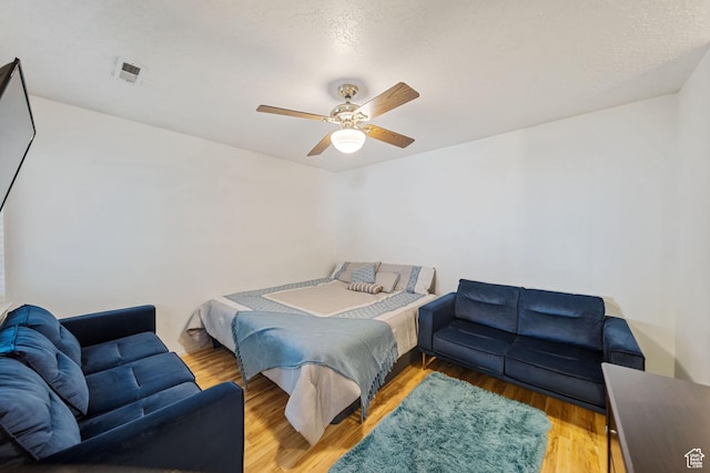 bedroom featuring wood finished floors, visible vents, and a ceiling fan