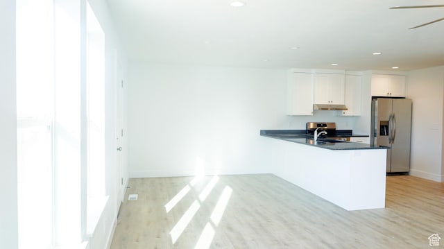 kitchen with dark countertops, light wood-style flooring, white cabinetry, under cabinet range hood, and stainless steel fridge with ice dispenser