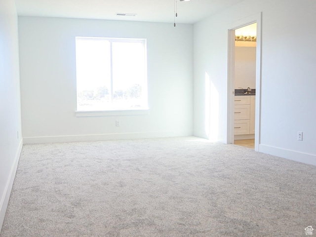 unfurnished room featuring carpet flooring, a sink, visible vents, and baseboards