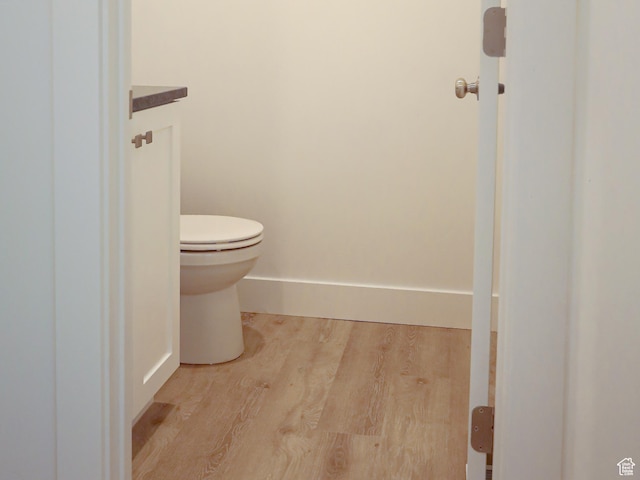 bathroom with toilet, baseboards, wood finished floors, and vanity