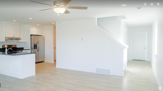 kitchen featuring light wood finished floors, stainless steel fridge, visible vents, dark countertops, and a sink