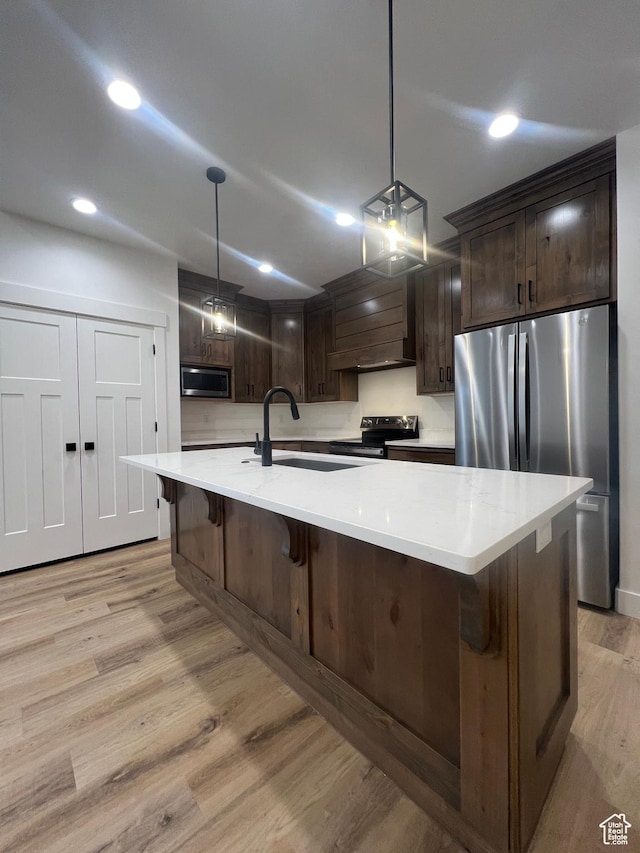 kitchen with recessed lighting, a sink, dark brown cabinets, light wood-style floors, and appliances with stainless steel finishes