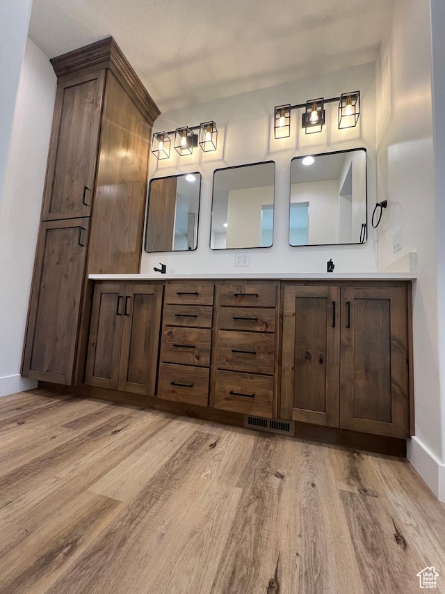 bathroom with double vanity, wood finished floors, and baseboards