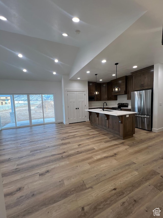 kitchen featuring dark brown cabinets, light countertops, lofted ceiling, appliances with stainless steel finishes, and a sink