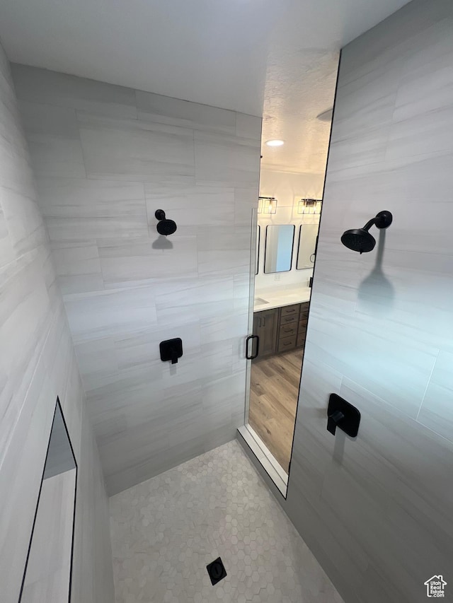 full bath featuring a tile shower and vanity