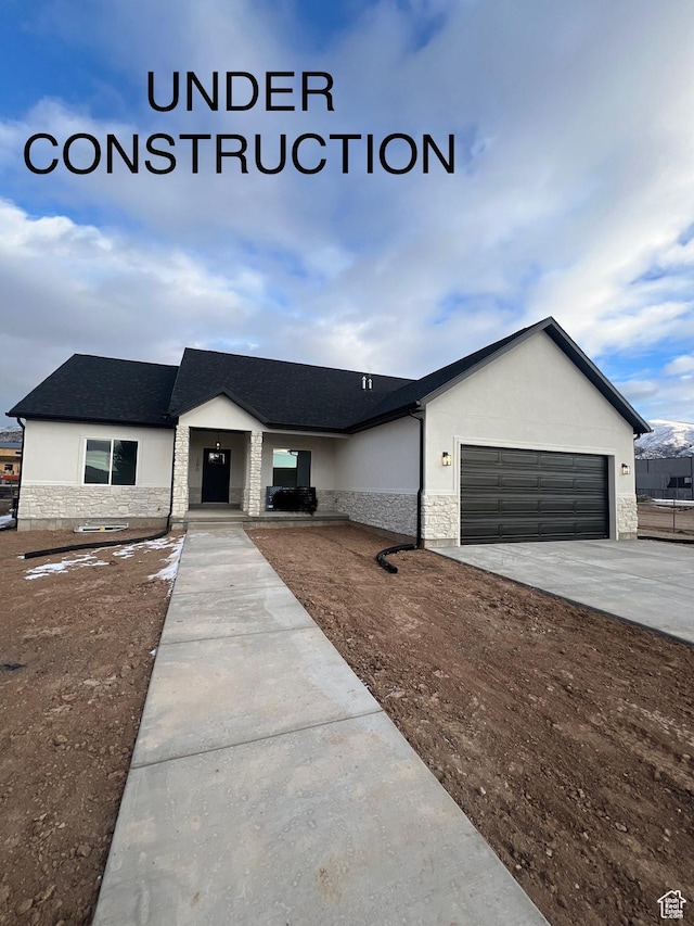 view of front facade featuring stucco siding, stone siding, a garage, and driveway
