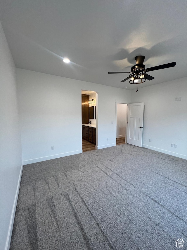 unfurnished bedroom featuring ensuite bathroom, a ceiling fan, carpet, and baseboards
