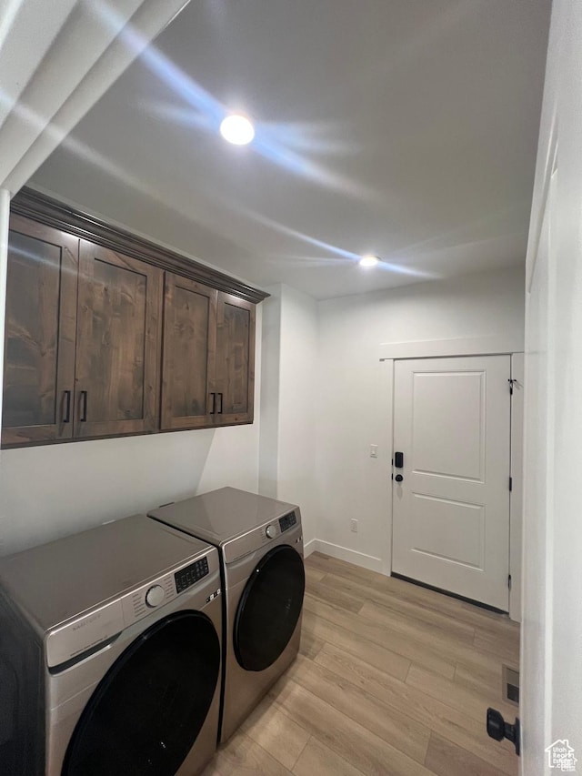 clothes washing area with visible vents, baseboards, washing machine and dryer, light wood-type flooring, and cabinet space