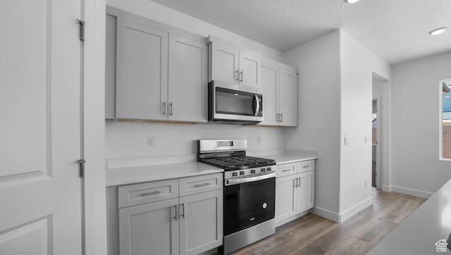 1726 S Wolverine Way Unit 174, Washington, UT 84780 - kitchen featuring stainless steel appliances, light countertops, baseboards, a textured ceiling, and wood finished floors