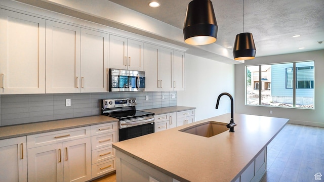 954 W 1880 S, Syracuse, UT 84075 - kitchen featuring stainless steel appliances, decorative backsplash, white cabinetry, a sink, and light wood-type flooring