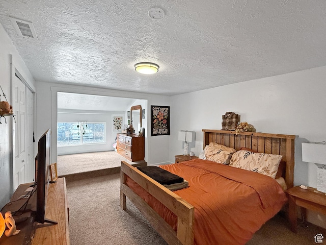 bedroom with carpet flooring, visible vents, and a textured ceiling