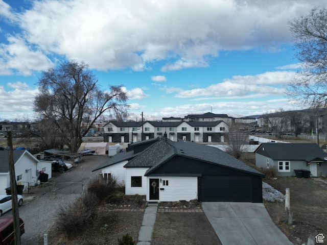 exterior space with a garage, a residential view, concrete driveway, and roof with shingles