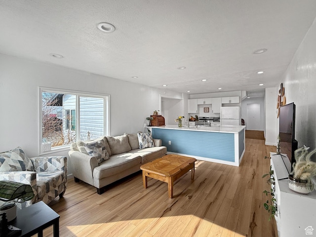living area with light wood-type flooring, baseboards, a textured ceiling, and recessed lighting
