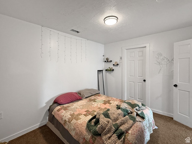 carpeted bedroom featuring a textured ceiling and baseboards