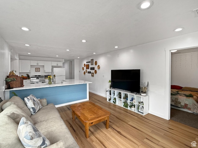 living room featuring light wood-type flooring, visible vents, baseboards, and recessed lighting