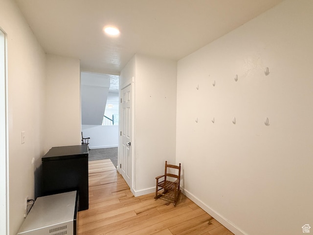 corridor featuring light wood-style flooring and baseboards