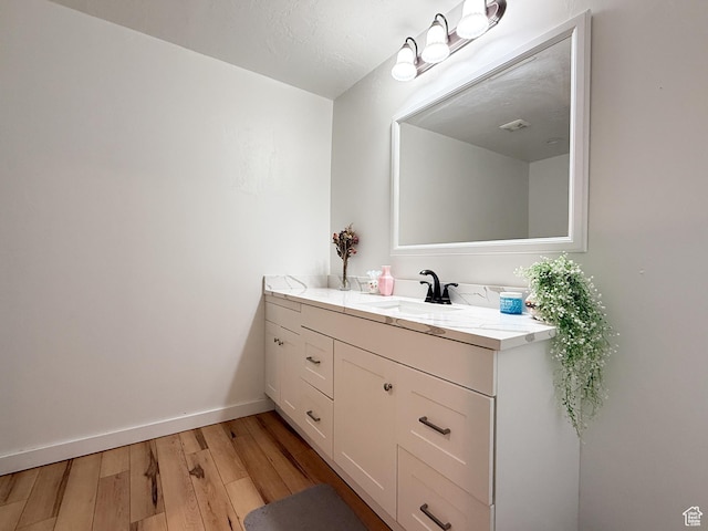 bathroom with vanity, baseboards, and wood finished floors