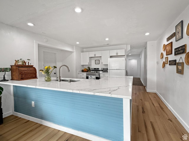 kitchen with white cabinets, freestanding refrigerator, a peninsula, stainless steel range with electric cooktop, and a sink