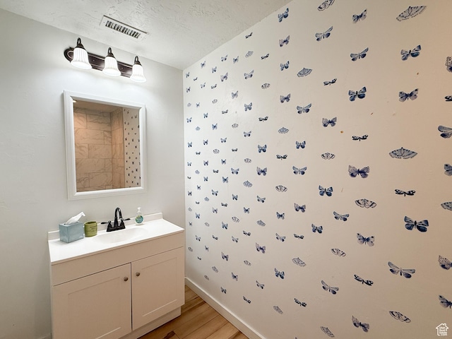 bathroom with baseboards, visible vents, wood finished floors, a textured ceiling, and vanity