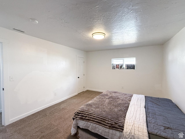 bedroom with carpet floors, visible vents, a textured ceiling, and baseboards