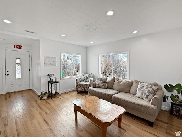 living area featuring a textured ceiling, recessed lighting, visible vents, baseboards, and light wood-type flooring