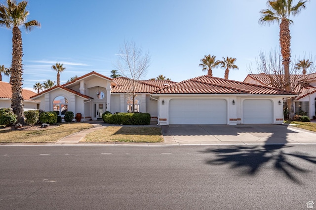mediterranean / spanish-style home with a garage, driveway, a tiled roof, and stucco siding