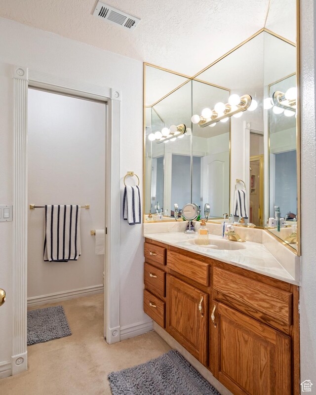 150 S Crystal Lakes Dr Unit 48, St George, UT 84770 - bathroom with a textured ceiling, vanity, visible vents, and baseboards