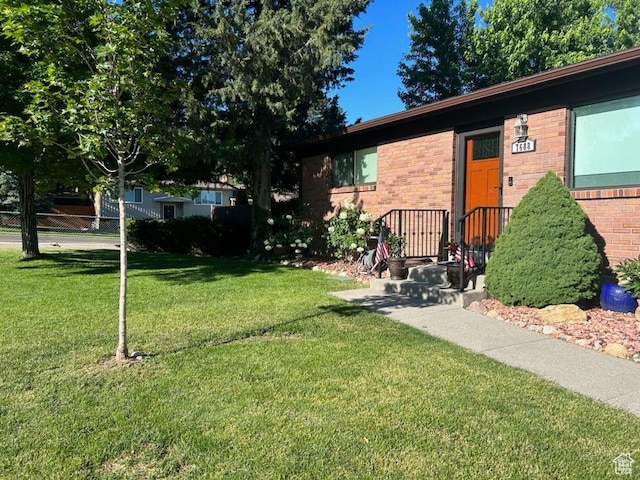 view of front of property with brick siding, a front yard, and fence