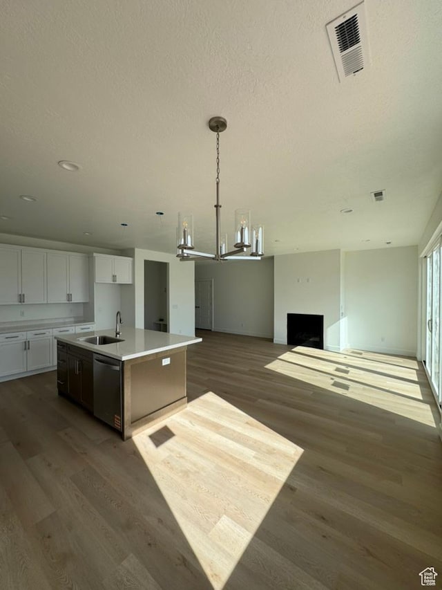 kitchen with visible vents, wood finished floors, stainless steel dishwasher, and a center island with sink