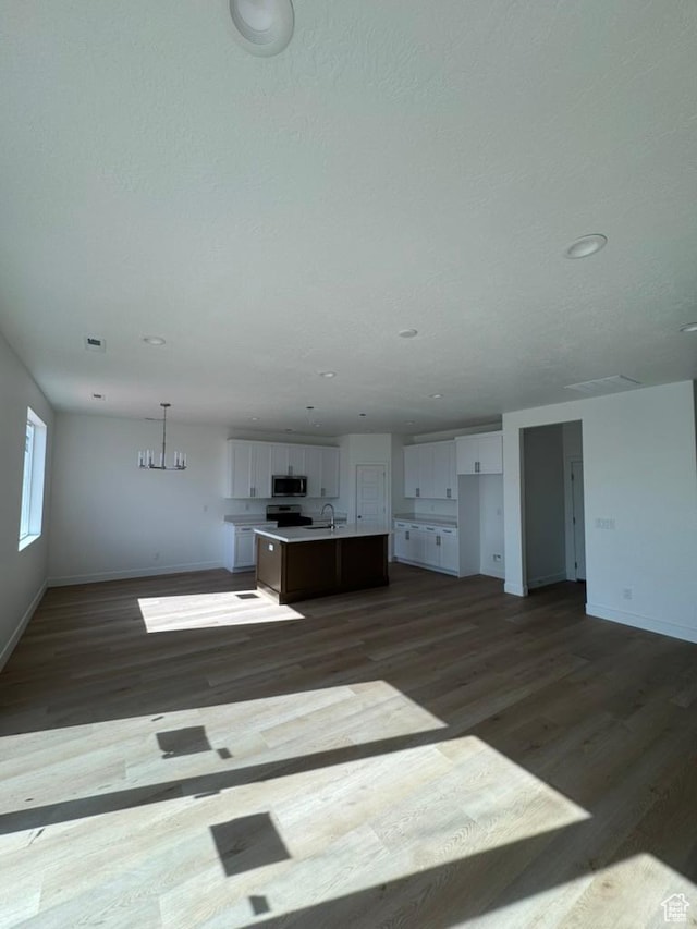 unfurnished living room featuring a sink, recessed lighting, dark wood finished floors, and baseboards