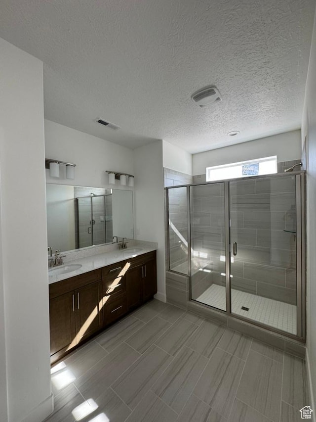 bathroom with a shower stall, double vanity, and a sink