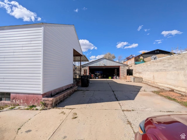 view of side of property featuring fence, an outdoor structure, and a detached garage