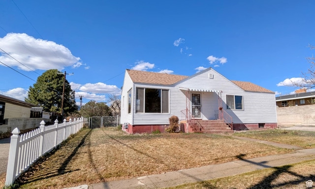 bungalow featuring fence, a shingled roof, and a front lawn