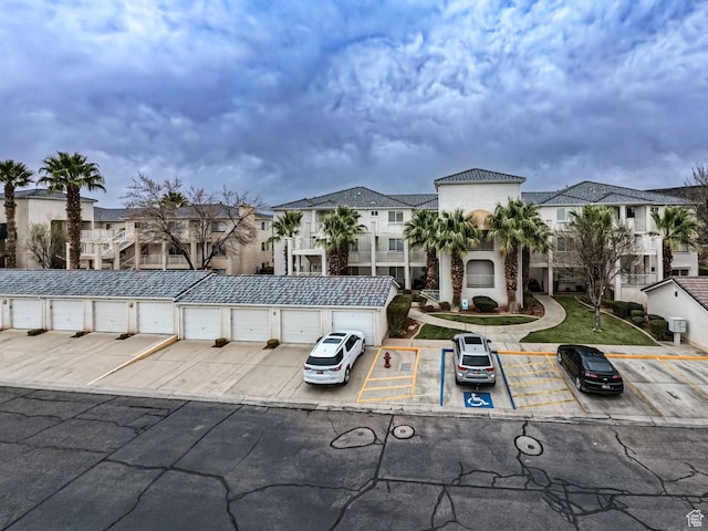 view of front of property featuring uncovered parking, a residential view, community garages, and stucco siding