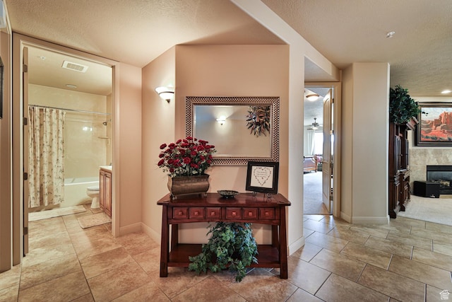 corridor featuring visible vents, a textured ceiling, and baseboards