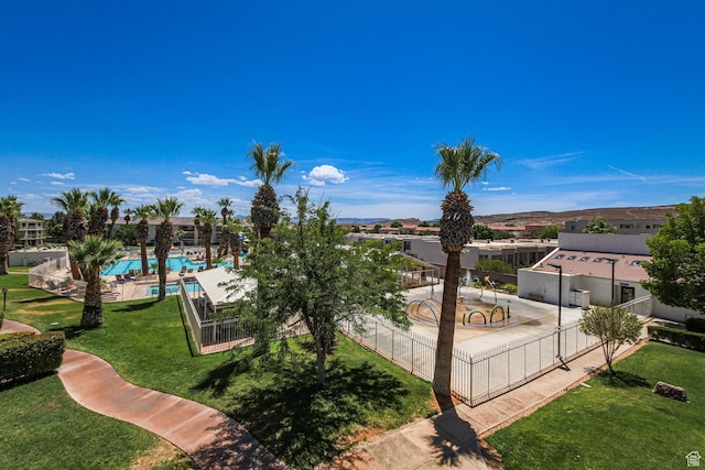 view of home's community with fence, a pool, and a lawn