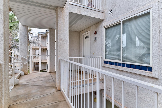 property entrance with a balcony and stucco siding