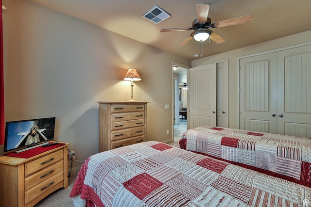 bedroom featuring visible vents, baseboards, a ceiling fan, carpet flooring, and two closets