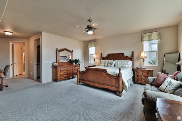 bedroom featuring a textured ceiling, multiple windows, a ceiling fan, and light colored carpet
