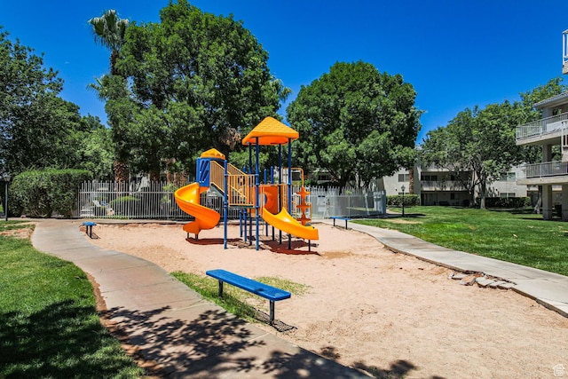 community play area featuring a lawn and fence