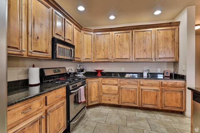 kitchen featuring appliances with stainless steel finishes, brown cabinets, dark stone countertops, and recessed lighting