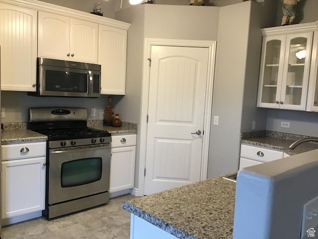 kitchen featuring glass insert cabinets, white cabinetry, and appliances with stainless steel finishes