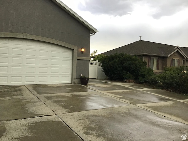 view of side of home featuring driveway, a garage, and stucco siding