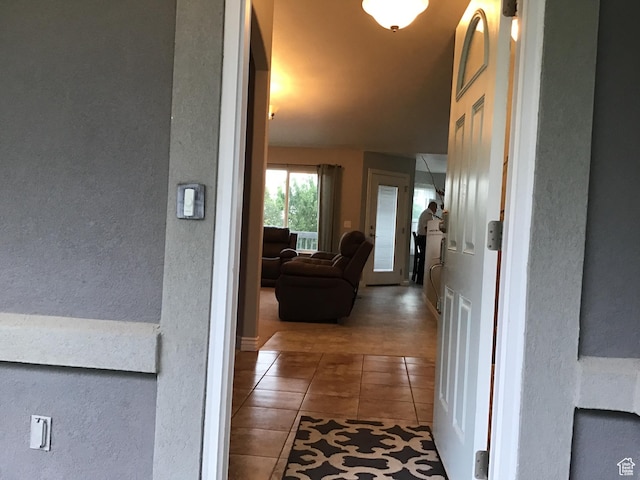 hallway with a textured wall and tile patterned floors