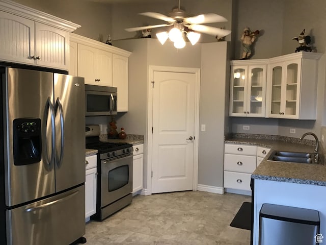kitchen with glass insert cabinets, appliances with stainless steel finishes, white cabinets, and a sink