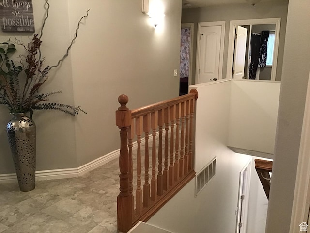 hallway with visible vents, an upstairs landing, and baseboards