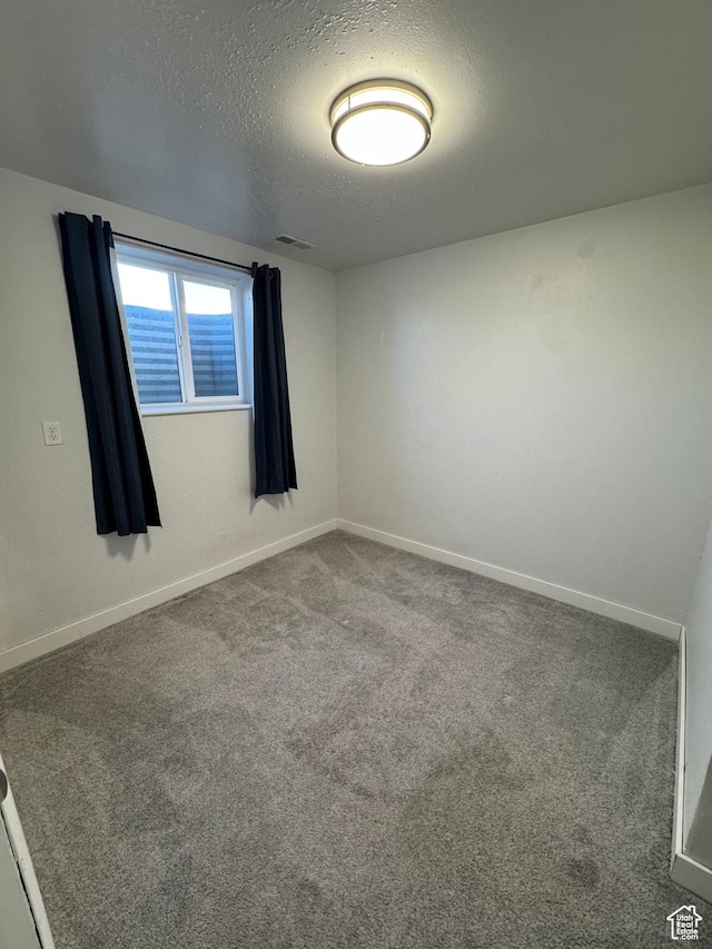 unfurnished room with carpet, visible vents, a textured ceiling, and baseboards
